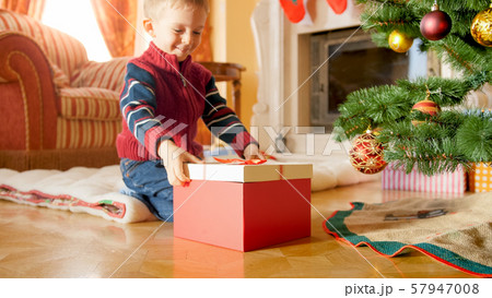 Portrait of cheerful smiling little boy looking at big box with Christmas present 57947008