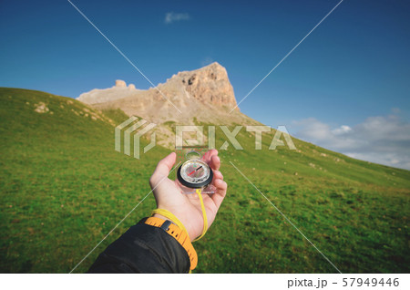 Male hand with a magnetic compass ea against the backdrop of a beautiful landscape at sunset. The Male hand with a magnetic compass ea against the backdrop of a beautiful landscape at sunset. The 57949446