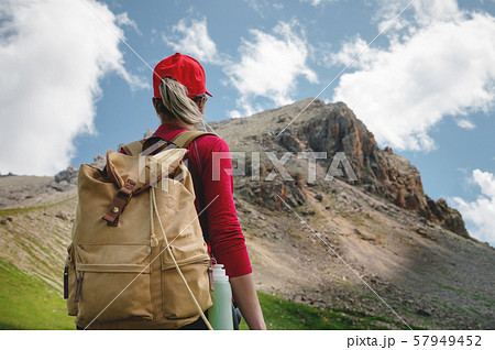 View from the back Girl athlete in a red cap sunglasses and a yellow backpack stands on a green 57949452