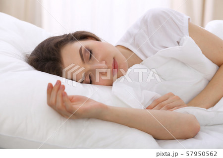 Beautiful young woman sleeping while lying in her bed. Concept of pleasant and rest reinstatement Beautiful young woman sleeping while lying in her bed. Concept of pleasant and rest reinstatement 57950562