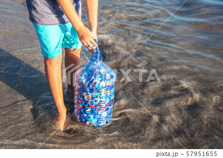 Child gathering plastic bottle caps at seaside 57951655