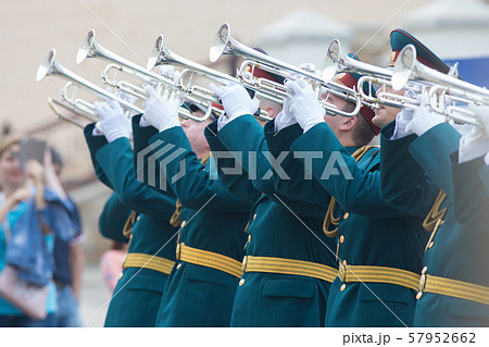 A wind instrument parade - men in green official costumes with yellow belts playing trumpets 57952662