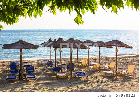 Row of wooden umbrellas at sandy beach, sea during the sunset 57958123