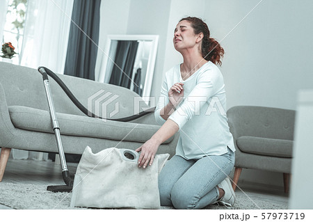 Curly red-haired woman feeling awful while using vacuum cleaner 57973719