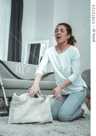 Young wife sneezing while cleaning her vacuum cleaner at home 57973723