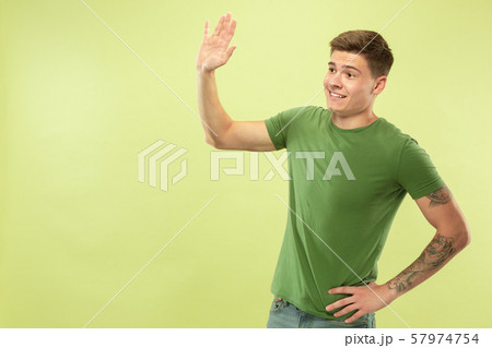 Caucasian young man's half-length portrait on green background Caucasian young man's half-length portrait on green background 57974754