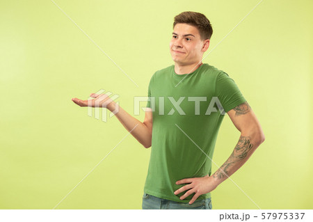 Caucasian young man's half-length portrait on green background 57975337