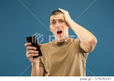 Caucasian young man's half-length portrait on blue background Caucasian young man's half-length portrait on blue background 57976147