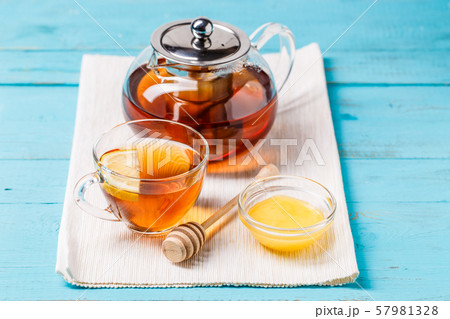 Glass cup of tea with lemon, glass teapot and honey. 57981328