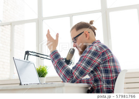 Radio, DJ, blogging and people concept - Smiling man sitting in front of microphone, host at radio 57981766