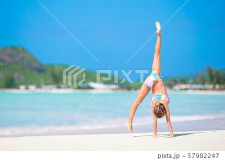 Active little girl at beach having a lot of fun. Cute kid making sporty exercises on the seashore 57982247