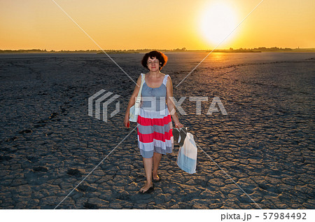 Mature woman stands at bottom of dried lake 57984492