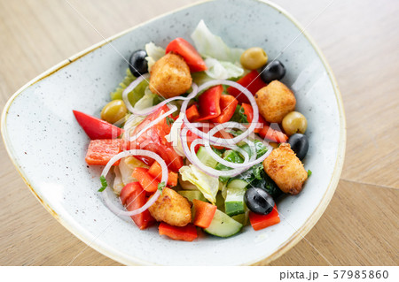 Traditional greek salad with fresh vegetables, feta cheese and olives. Wooden table in restaurant Traditional greek salad with fresh vegetables, feta cheese and olives. Wooden table in restaurant 57985860