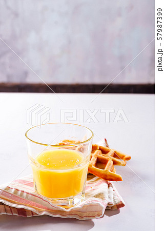 Orange juice and belgian or french waffles for breakfast on light background Orange juice and belgian or french waffles for breakfast on light background 57987399