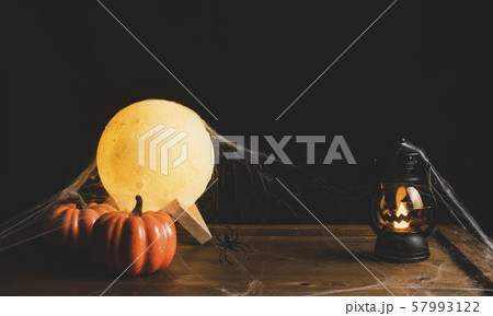 Halloween decorations with pumpkin,lantern and the moon on wooden table with a black backdrop. Halloween decorations with pumpkin,lantern and the moon on wooden table with a black backdrop. 57993122