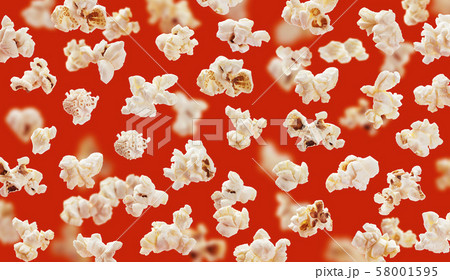 Delicious pop corn grains closeup on red background Delicious pop corn grains closeup on red background 58001595