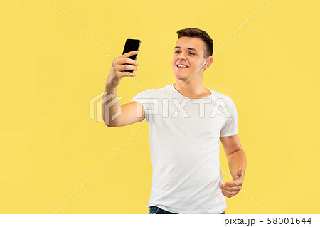 Caucasian young man's half-length portrait on yellow background 58001644