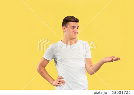 Caucasian young man's half-length portrait on yellow background 58001726