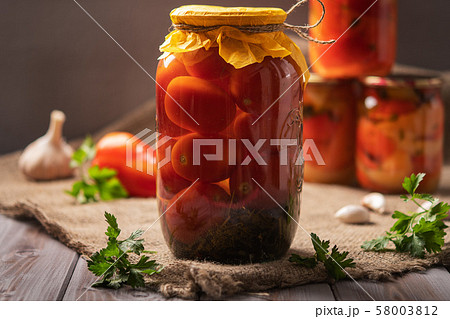 Homemade jars of pickled tomatoes on a rustic wooden background. Pickled and canned product. Next Homemade jars of pickled tomatoes on a rustic wooden background. Pickled and canned product. Next 58003812