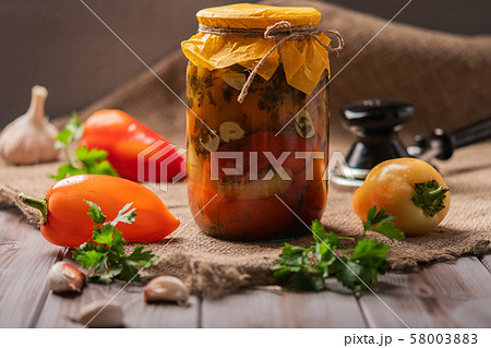 Jar of pickled peppers on a rustic wooden background. Pickled and canned product. Next ingredients 58003883