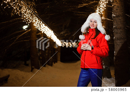 female friend in colorful jackets having fun and at night at Christmas time. 58003965