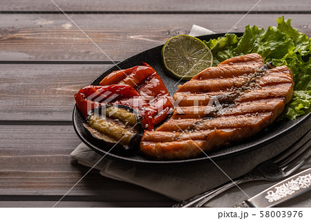 Homemade grilled salmon steak on lettuce leaves. On a plate on a linen napkin. Next to baked Homemade grilled salmon steak on lettuce leaves. On a plate on a linen napkin. Next to baked 58003976