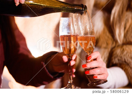 Pouring champagne into glass at party, close up, winter Pouring champagne into glass at party, close up, winter 58006129