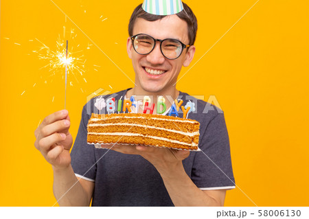 Crazy cheerful young asian guy with glasses holding a burning candle in his hands and a 58006130
