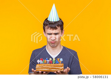 Funny positive guy in glasses holds in his hands a homemade cake with the inscription happy birthday Funny positive guy in glasses holds in his hands a homemade cake with the inscription happy birthday 58006131