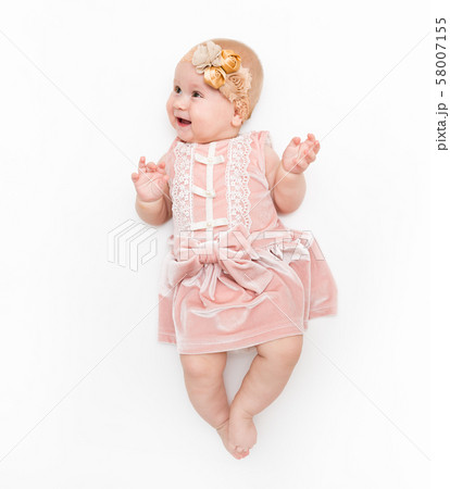 Portrait of a sweet infant wearing a pink dress, headband bow, isolated on white in studio. Portrait of a sweet infant wearing a pink dress, headband bow, isolated on white in studio. 58007155