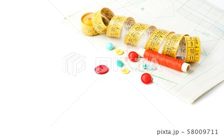 Sewing supplies on white sewing thread, scissors, pattern, centimeter, buttons Sewing supplies on white sewing thread, scissors, pattern, centimeter, buttons 58009711
