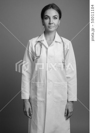Young beautiful woman doctor against gray background Young beautiful woman doctor against gray background 58011184