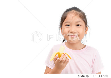 Little asian cute girl eats banana isolated on Little asian cute girl eats banana isolated on 58011786