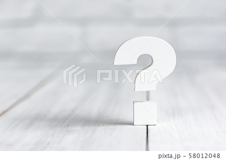 Question mark on white wood table over white brick 58012048