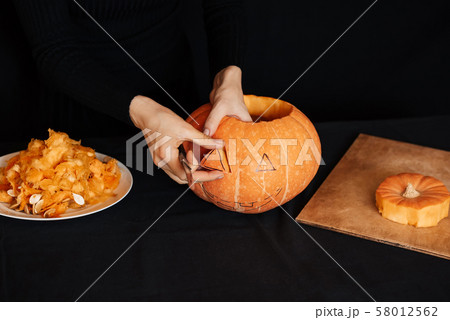 Girl hands makes an orange pumpkin for Halloween. Preparation of Jack's lantern Girl hands makes an orange pumpkin for Halloween. Preparation of Jack's lantern 58012562