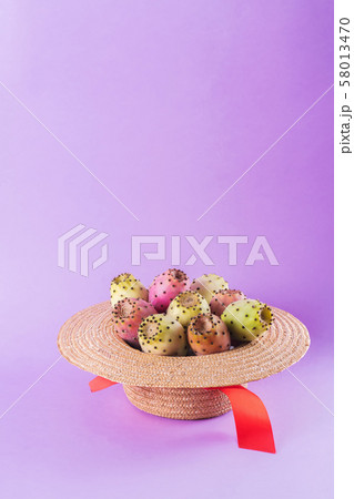 Opuntia fruit in a straw hat on a trendy purple Opuntia fruit in a straw hat on a trendy purple 58013470