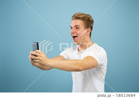 Caucasian young man's half-length portrait on blue background 58013684