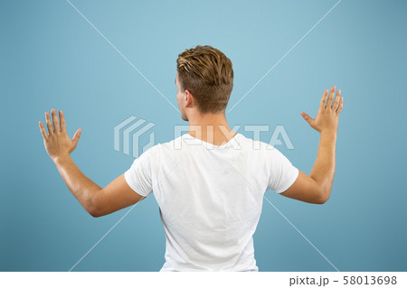 Caucasian young man's half-length portrait on blue background 58013698