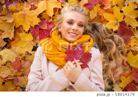 Portrait of pretty blonde teen girl lying on the carpet of yellow and red leaves Portrait of pretty blonde teen girl lying on the carpet of yellow and red leaves 58014179