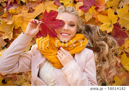 Portrait of pretty blonde teen girl lying on the carpet of yellow leaves 58014182