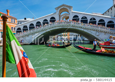 Italian maritime flag with Rialto bridge with gondolas in the bacground. Grand Canal, Venice, Italy 58014415