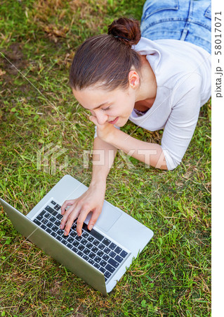 Young woman lying on green grass lawn in city park Young woman lying on green grass lawn in city park 58017071