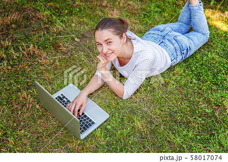 Young woman lying on green grass lawn in city park 58017074