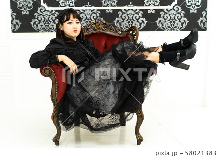 ゴスロリのコスプレをして椅子に座る女性 58021383