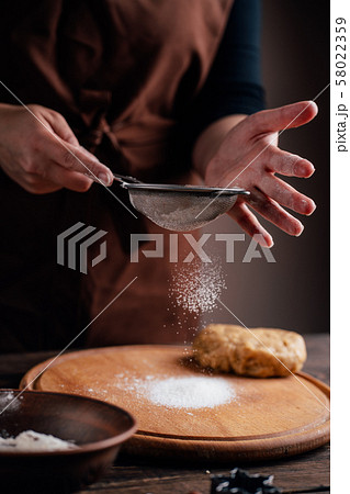 Woman sprinkling flour on gingerbread dough Woman sprinkling flour on gingerbread dough 58022359
