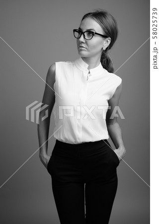 Portrait of young beautiful businesswoman against gray background Portrait of young beautiful businesswoman against gray background 58025739