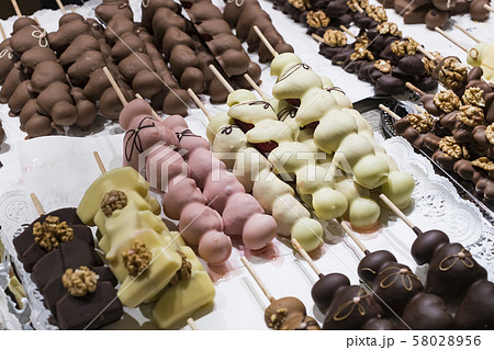 Fruits bananas, strawberries, nuts, apples, peaches drenched in white and dark chocolate.  58028956