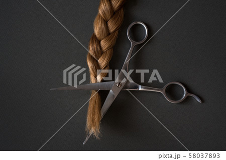 Part blond braids and scissors. Black background. 58037893