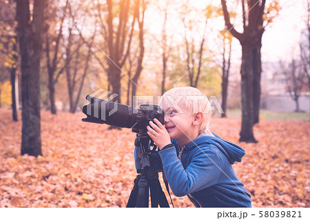 Little blond boy takes pictures on a SLR camera. Little blond boy takes pictures on a SLR camera. 58039821