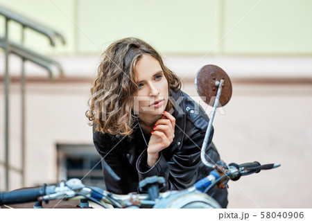 Pretty lady in leather coat and wild curly hair Pretty lady in leather coat and wild curly hair 58040906